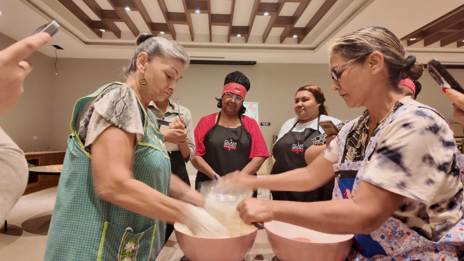 Mujeres emprendedoras batiendo mezclas en bowls durante una sesión de cocina grupal impartida por profesionales.