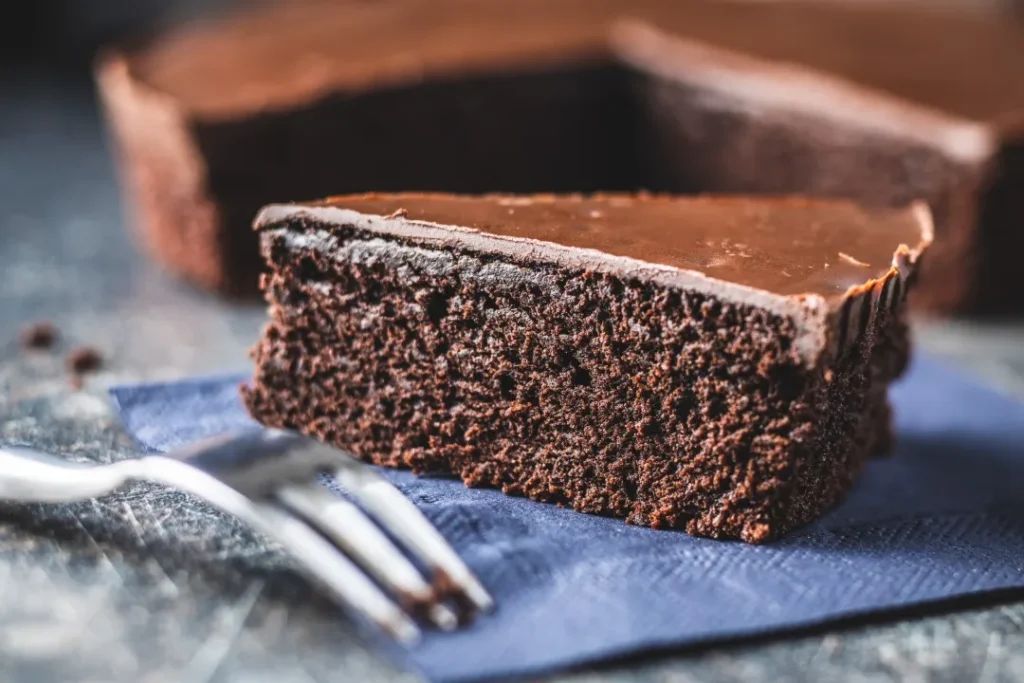 Delicioso pastel de chocolate con rodajas de naranja fresca y trozos de cacao sobre un mantel de rayas
