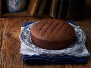 Esponjoso pastel de chocolate recién horneado servido sobre un plato clásico azul y blanco de época.